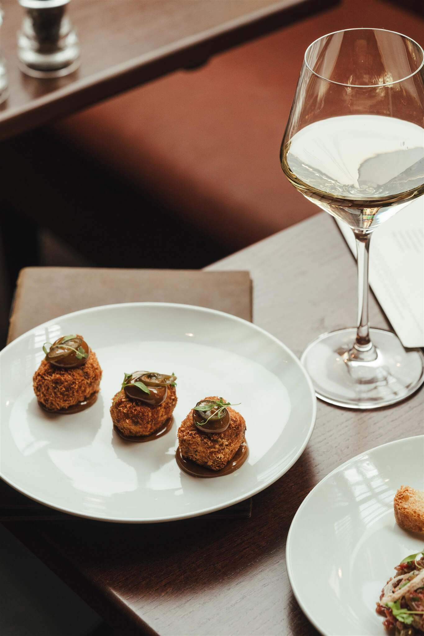 Three MRBL croquettes with onion glaze and a glass of white